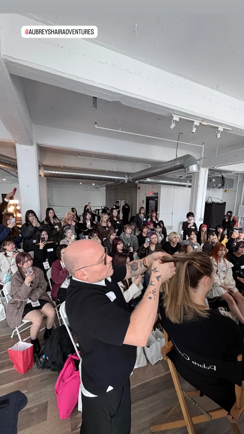 Aubrey styling a model in front of a full room of students