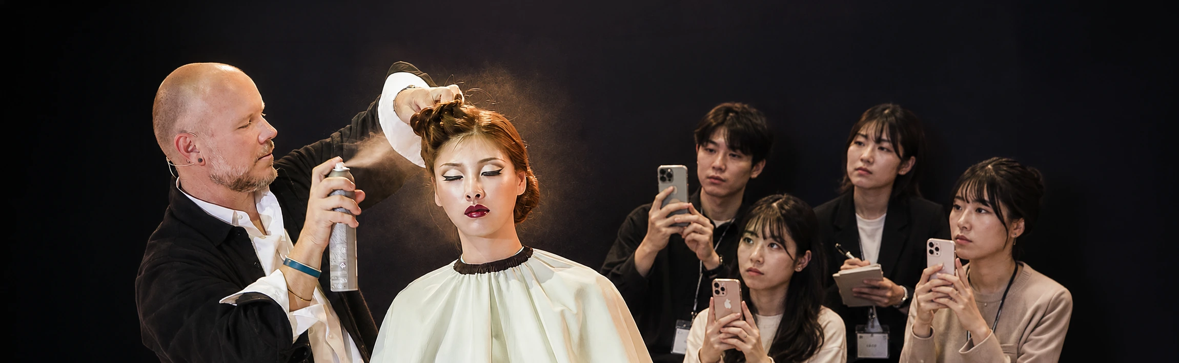 Aubrey styling a model while students film and take notes
